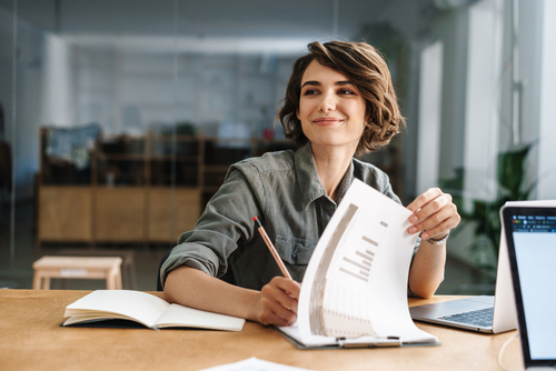 Das Bild zeigt: Frau vor Laptop, geht ihre Unterlagen durch, Zeitmanagement Coaching, Ziele und Zeit, Zielsetzung, Kurse, Coaching Kurse